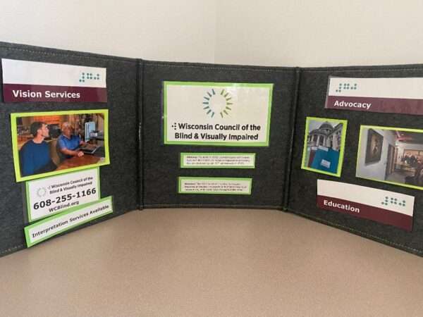 A folding table display showing the Council logo and photo examples of its vision services, advocacy and education work.
