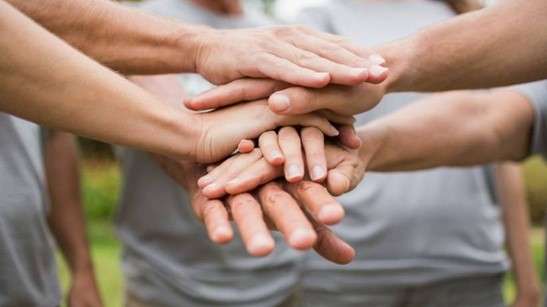 The hands of several people placed on top of each other in the middle.