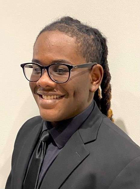 Photo of Jayquan Jaeger wearing a suit and tie and smiling.