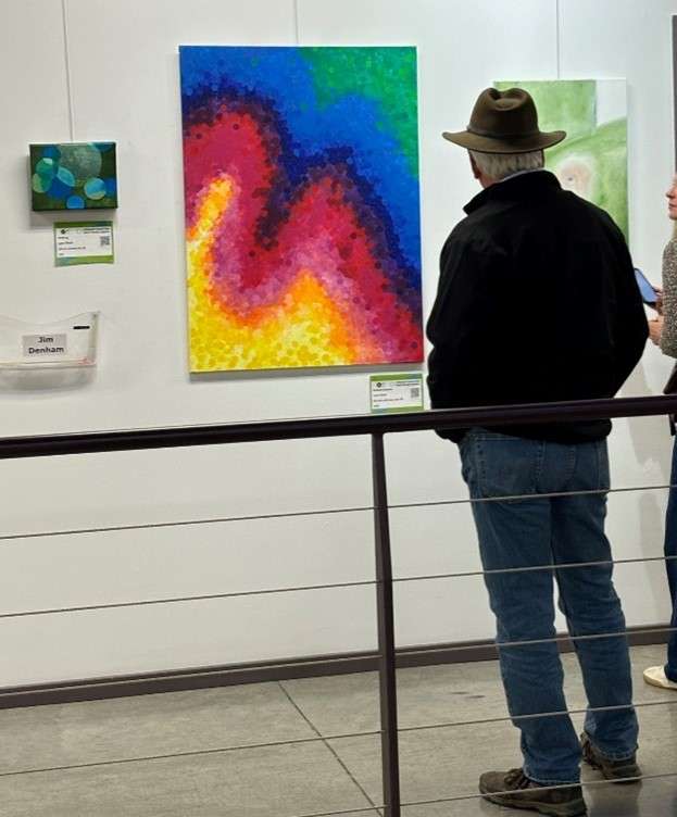 A man looking at paintings on a wall.