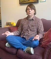 A person sitting cross-legged on a couch meditating.
