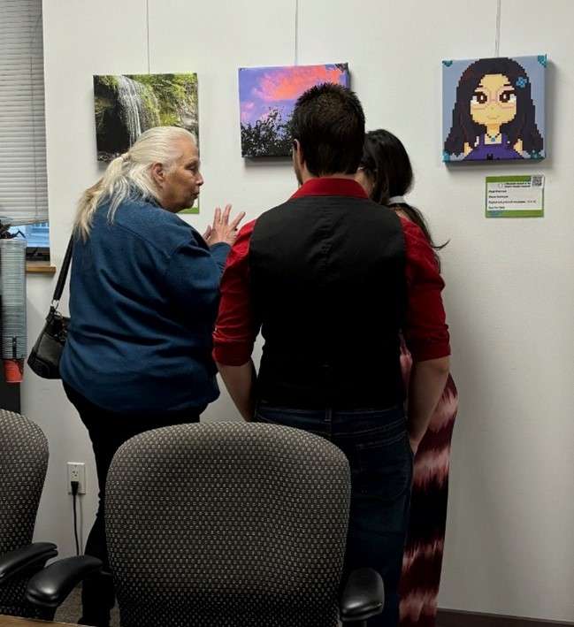 Three people in conversation in front of photography hanging on a wall.