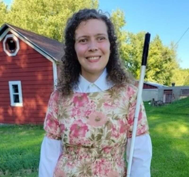 Chamomile Harrison standing in a yard with a barn or garage in the background.