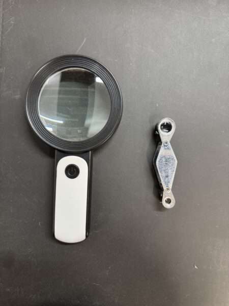 Two magnifiers side by side, the one on the left is large and claiming to be 30x, and the one of the right is much smaller and is 15x