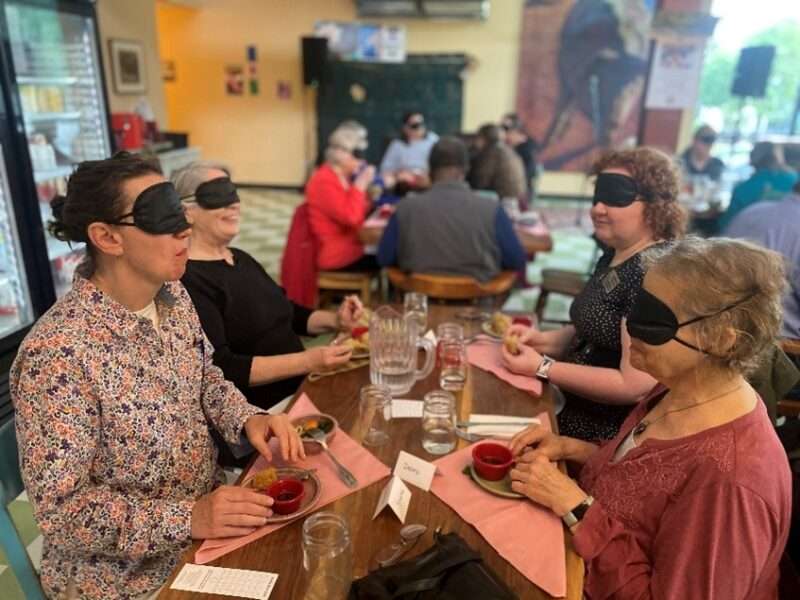 A group of blindfolded diners enjoying a meal.