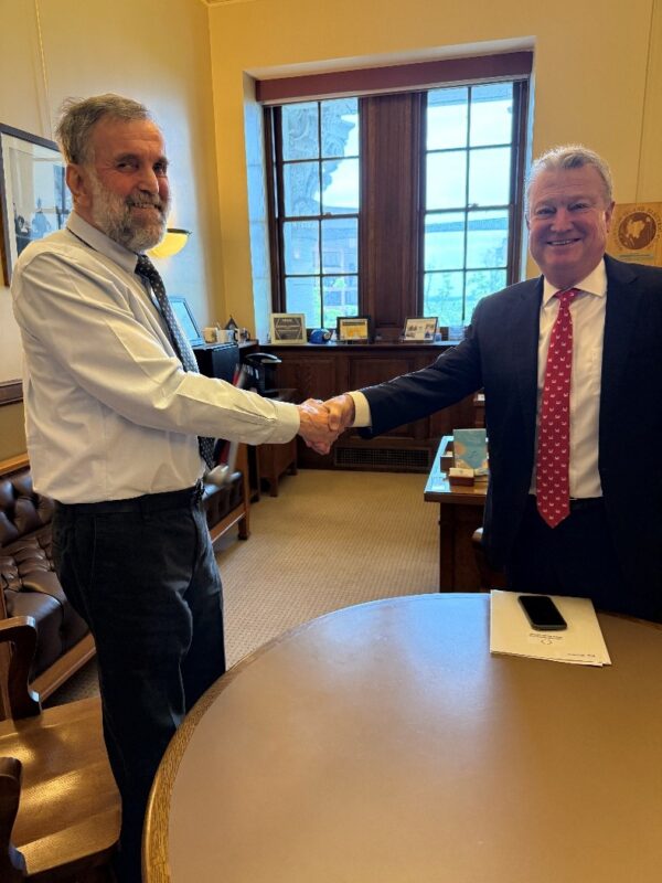 Two men shaking hands in a legislative office.