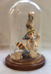 Pair of hand-tied salmon flies made from feathers, furs, tinsels and threads under a clear dome