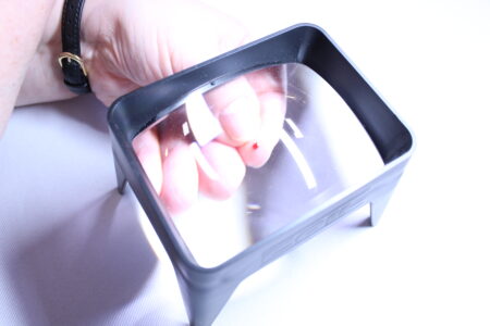 Pricked finger under a magnifier Squeezing blood from a finger under a magnifier.