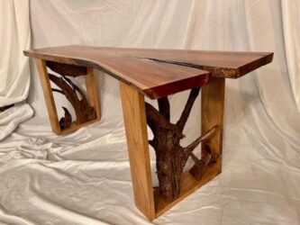 Long narrow wooden table with the top split at one end and raw tree branches built into the legs