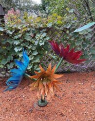 Metal sculpture of red, blue and orange flowers with many petals.