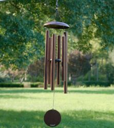A windchime hanging from a tree with a grassy background